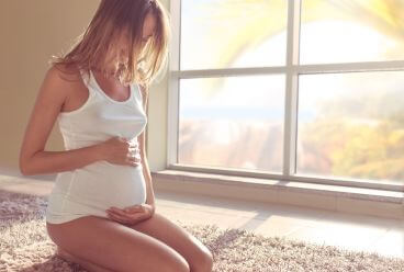 Femme enceinte sur tapis devant baie vitrée