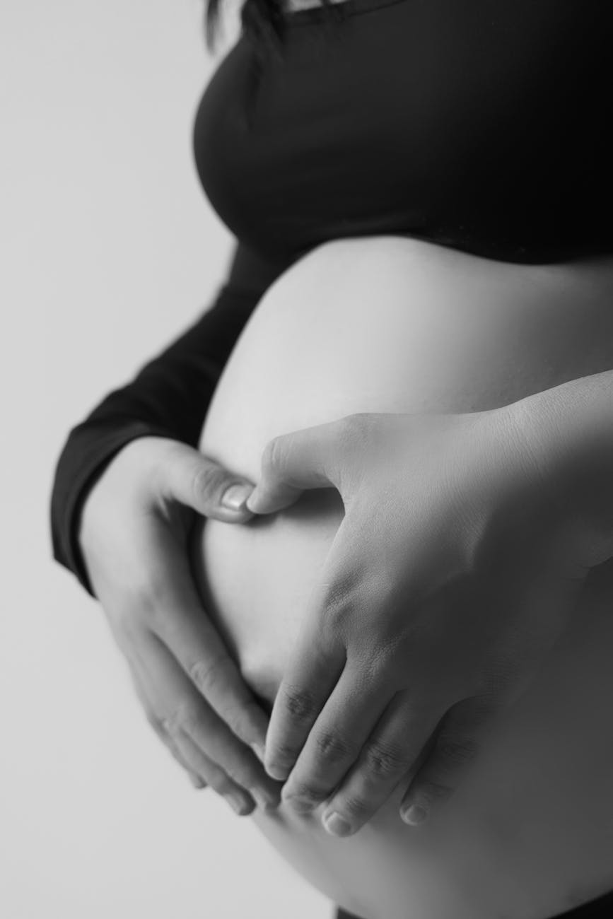 black and white pregnant belly with heart hands